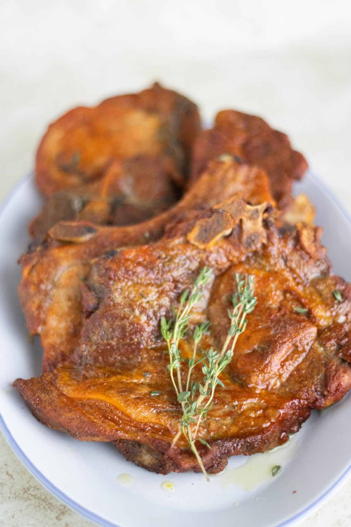 un plato llenos de varias chuletas al horno hechas al estilo puertorriqueño con tomillo fresco.