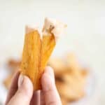 a hand holding 2 pieces of fried cassava with puerto rican mayoketchup.