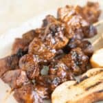 a plate with a few pinchos de pollo, puerto rican pork skewers with toasted bread on the side.