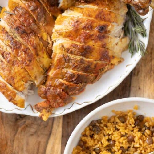 a plate with a carved turkey or pavochon and a bowl of pigeon peas and rice.