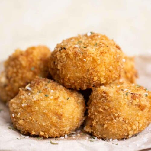 5 crispy fried balls of bacon croquettes on a plate.