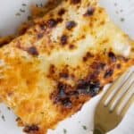 A piece of a baked lasagna and a fork on the side.