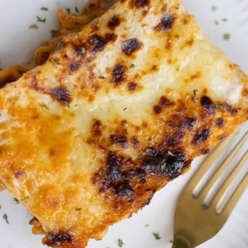 A piece of a baked lasagna and a fork on the side.