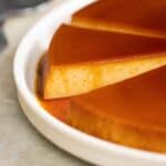 a big plate with a few big pieces of quesillo with a couple of spoons on the side.
