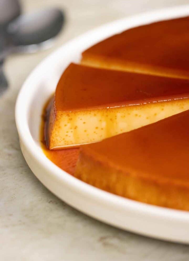 a big plate with a few big pieces of quesillo with a couple of spoons on the side.