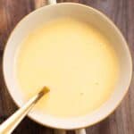 a small dish with a spiced beurre blanc with a few bay leaves on the side and a spoon inside the dish.