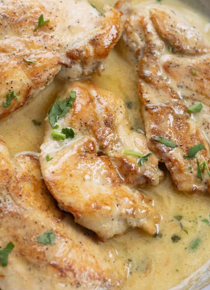chicken breast in a white sauce spiced beurre blanc garnished with parsley.