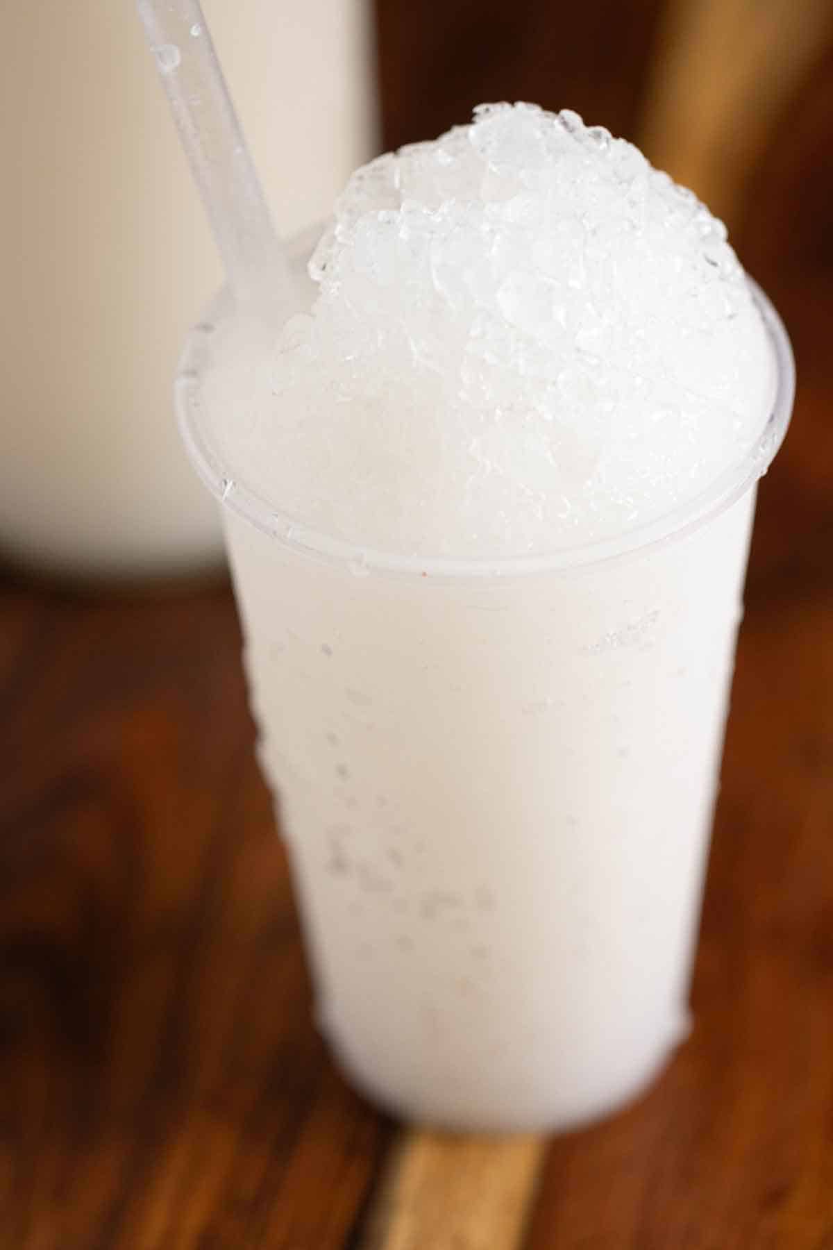 A Puerto Rican coconut piragua with a syrup bottle on the back.