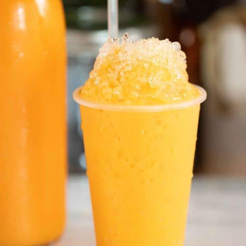 A Puerto Rican piragua de mantecado or ice cream flavor shaved ice with a bottle of syrup on the background.