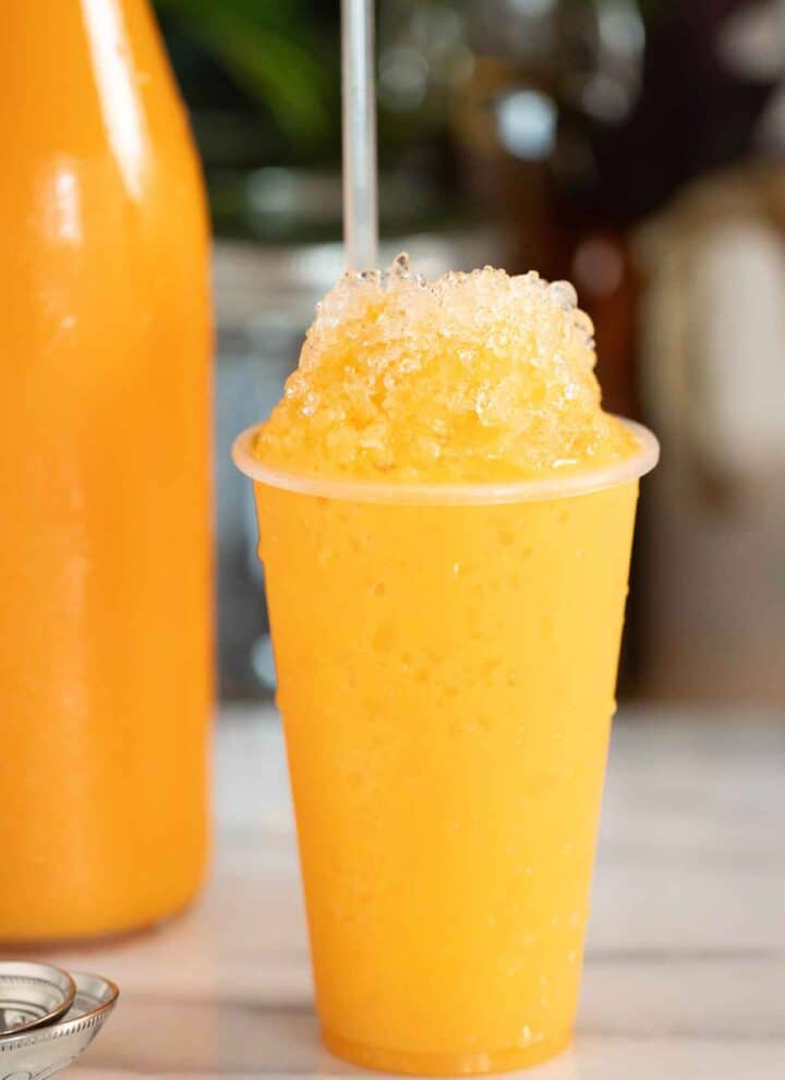 A Puerto Rican piragua de mantecado or ice cream flavor shaved ice with a bottle of syrup on the background.