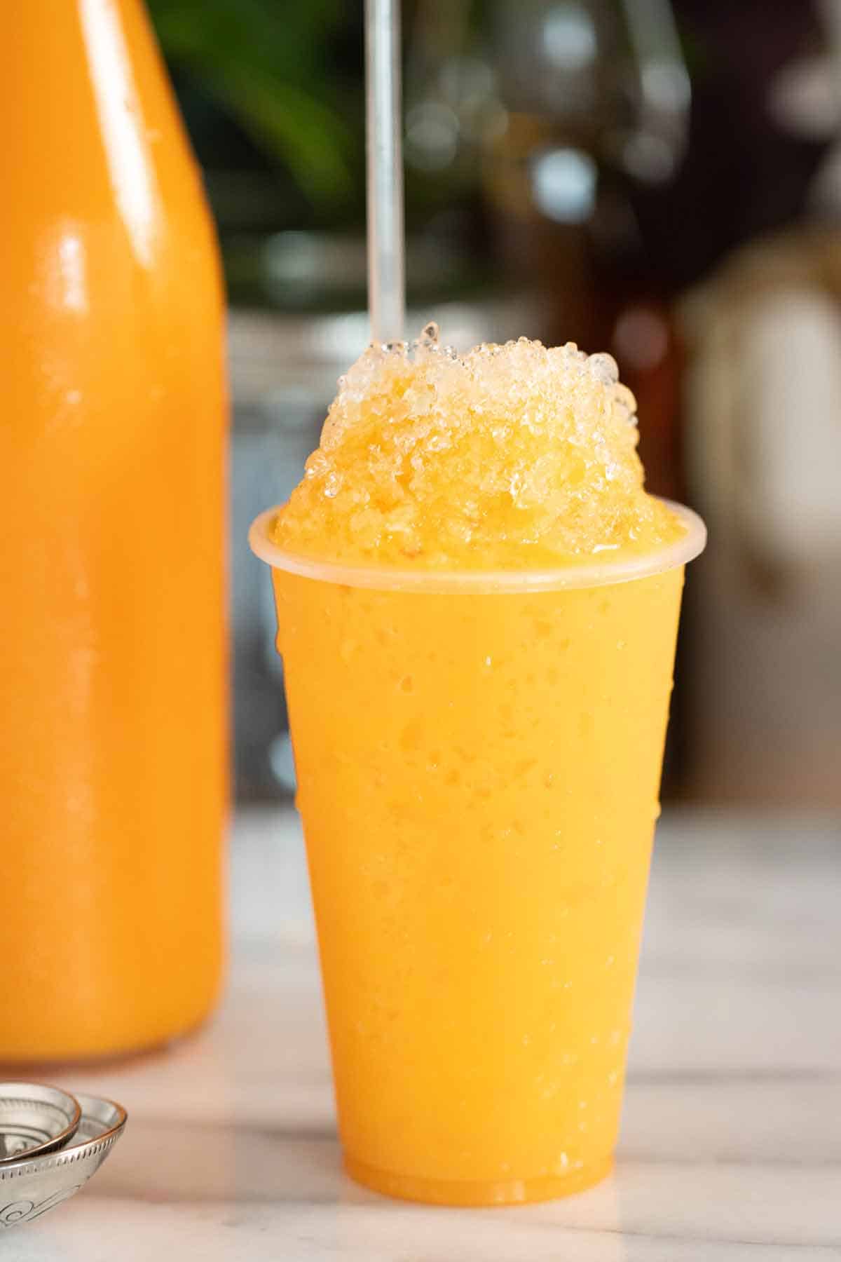 A Puerto Rican piragua de mantecado or ice cream flavor shaved ice with a bottle of syrup on the background.