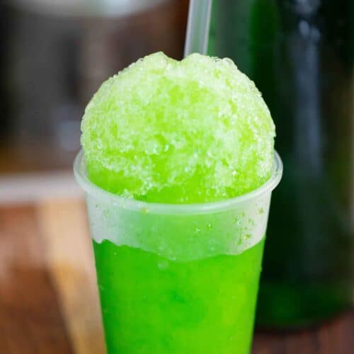 A mint flavor puerto rican piragua or mint shaved ice with a syrup bottle on the back.