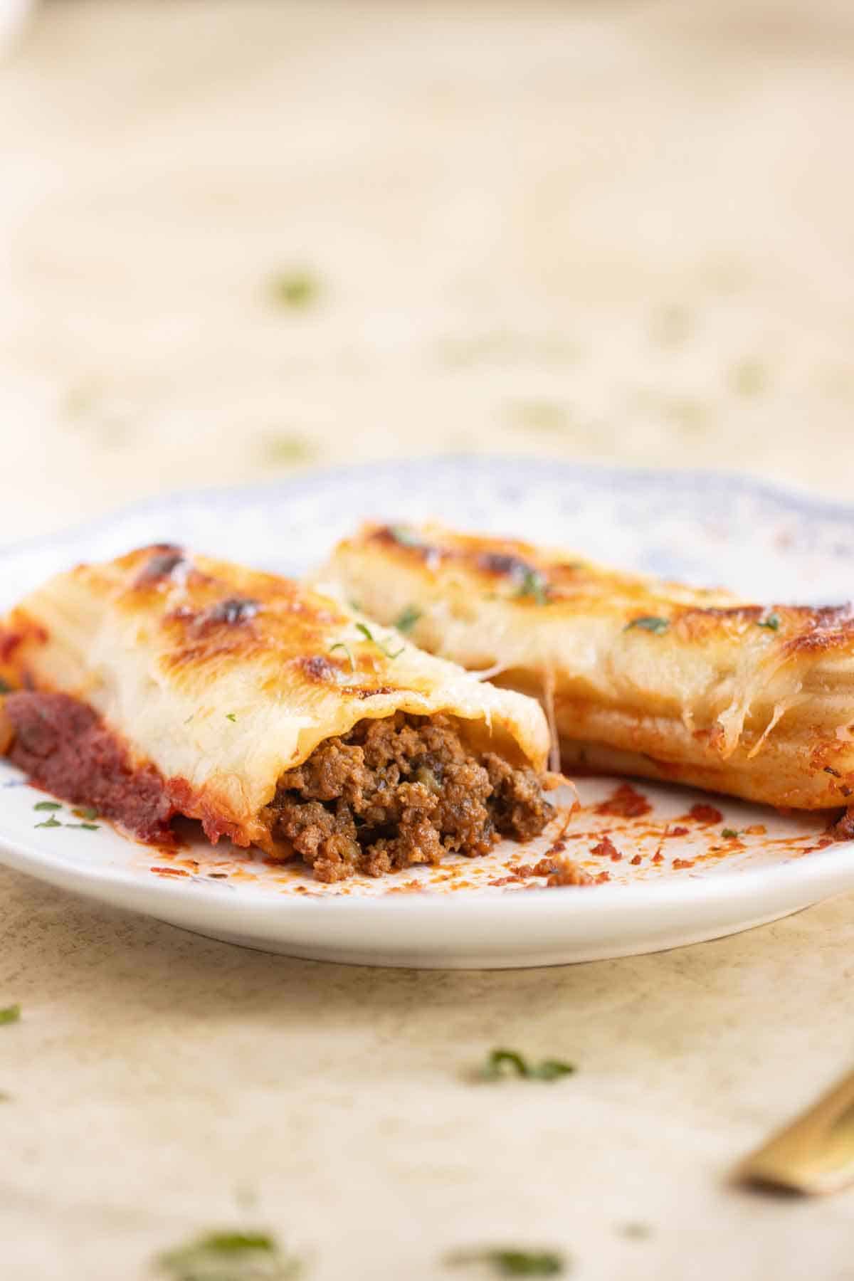 A plate with two canelones de carne made in a Puerto Rican style.