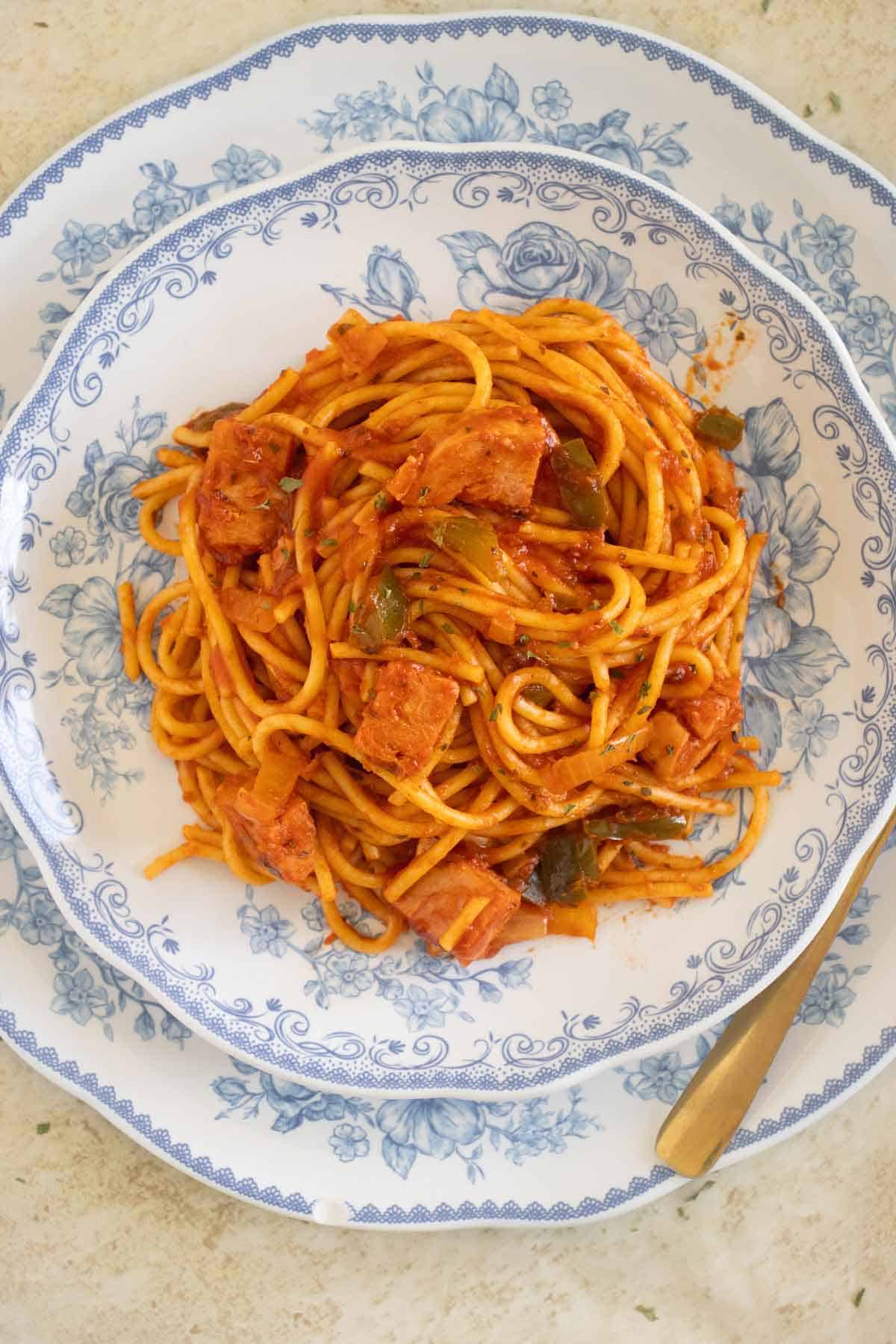 A small plate over a bigger plate with a puerto rican style spaghetti with spam.
