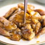 A late of chicken teriyaki and on the front a piece of chicken on chopsticks.