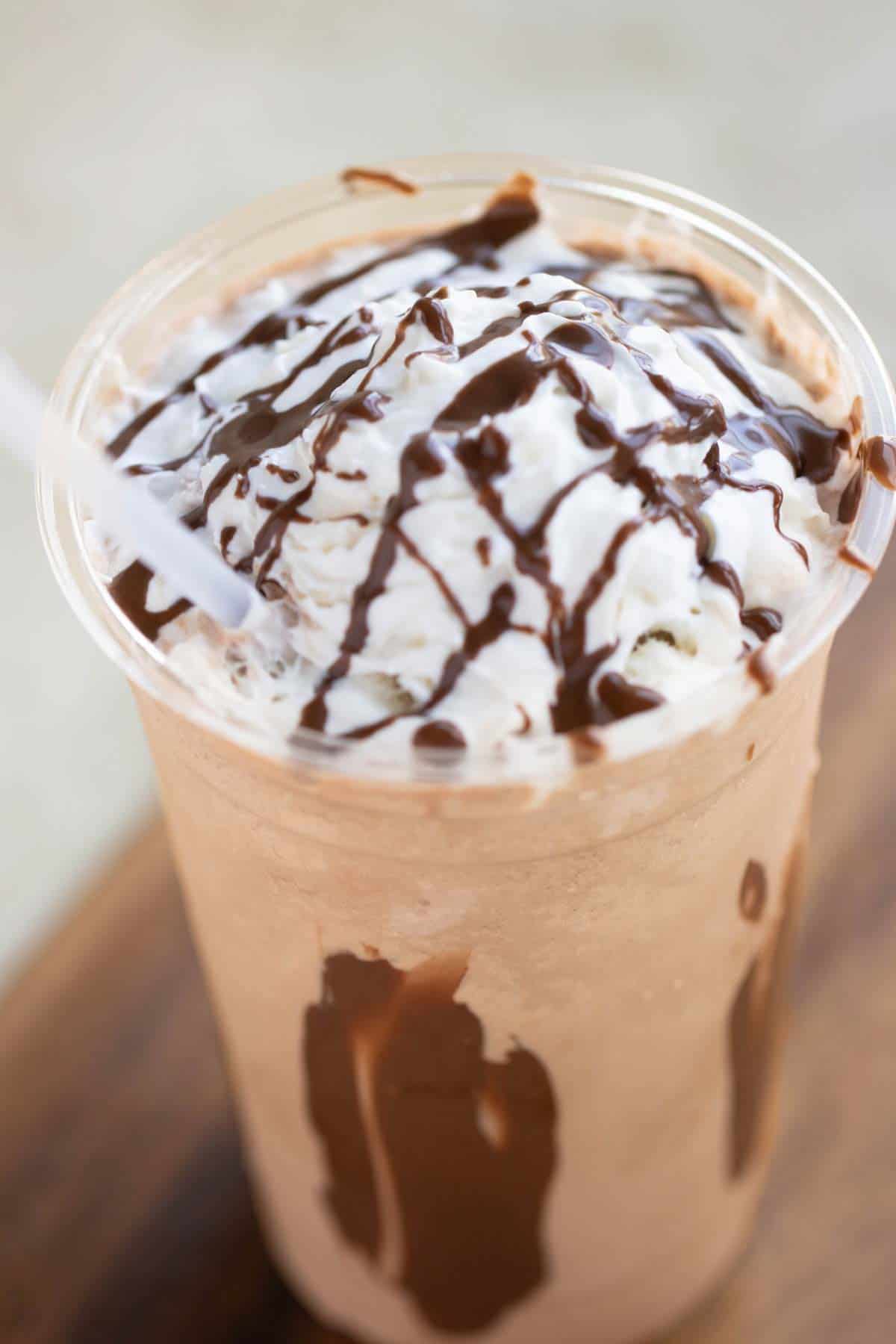 A cup of a chocolate frappe with whipped cream and chocolate drizzle.
