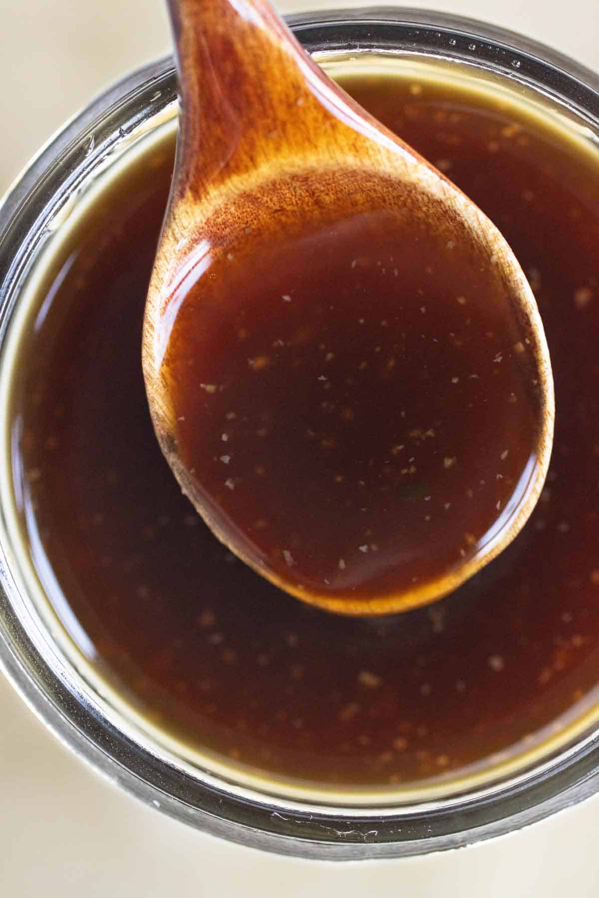 A jar and a spoonful of teriyaki sauce.