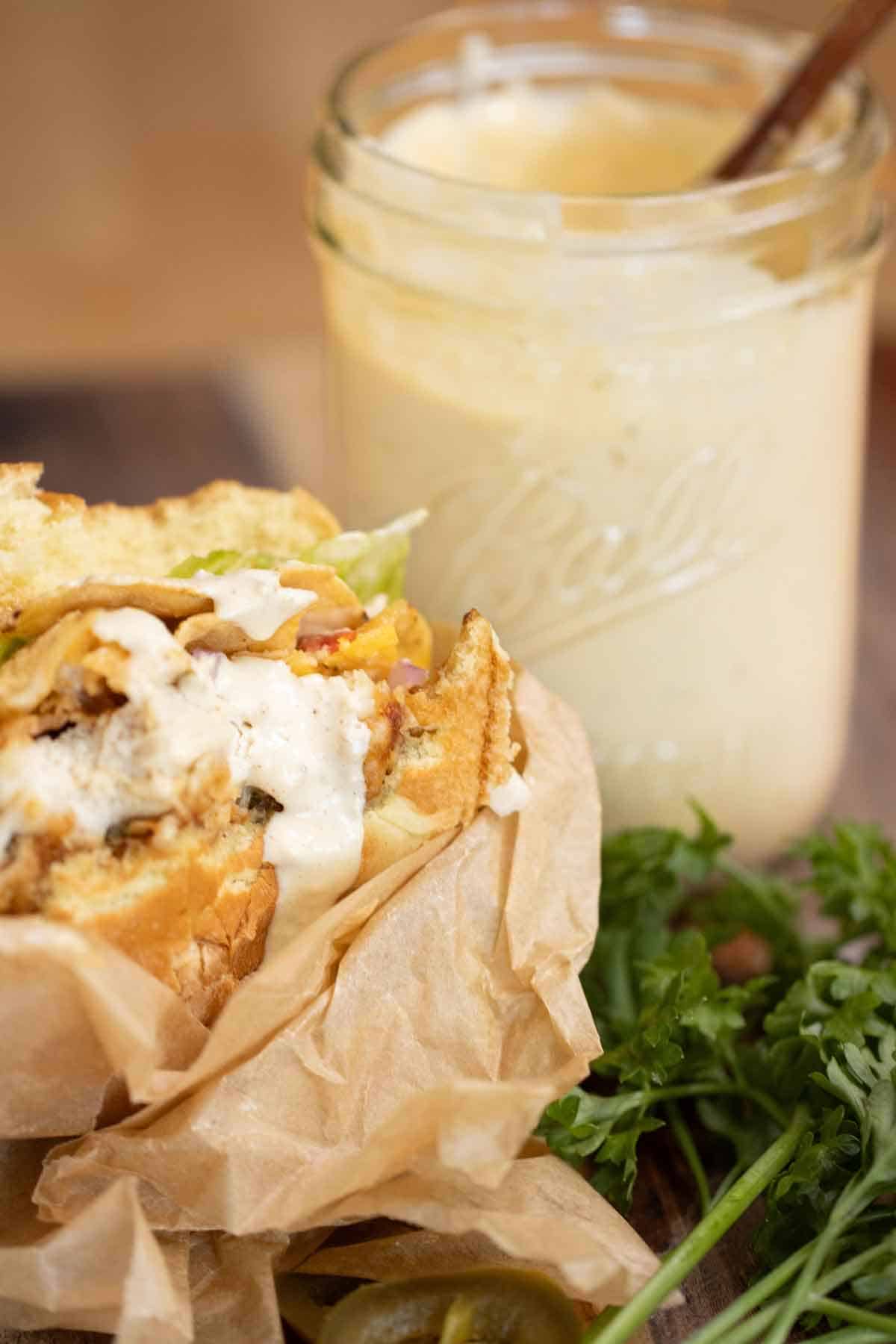 A chicken sauce with a creamy jalapeno sauce over it with a jar of sauce on the background.