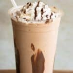 A large cup with a Nutella Frappe with whipped cream and chocolate drizzle with a straw.